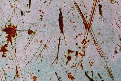 Silver skin has deep pits, jagged scars mark up the field, light catches the grit