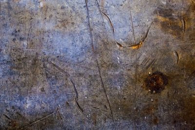 Steel scarred by usage, deep gouges cut the surface, rust blooms in the dark