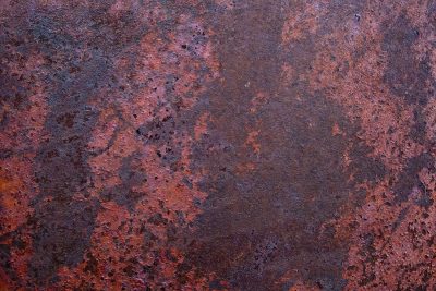 Iron meets the air, deep orange blooms on the steel, time eats through the plate