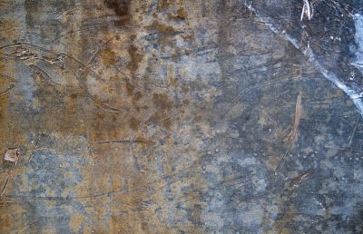 Silver skin has pits, grey marks trace the metal plate, grit holds the surface