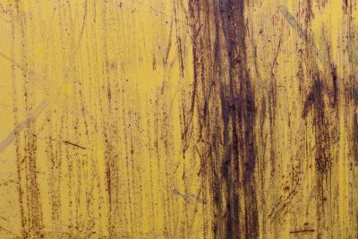 Yellow paint gives way, rust bleeds down the metal sheet, scars of time remain
