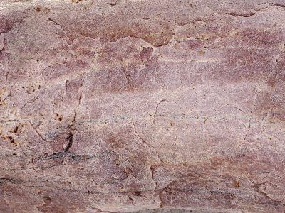 Tan grains flow in lines, horizontal veins hold light, time carves the pattern