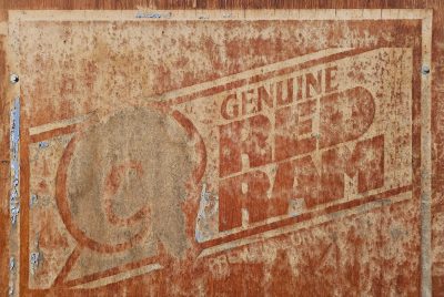 Weathered paint clings on, A ram ghost in peeling red, time chewing the wood.