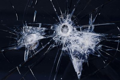 White fractures on a blue field, impact marks trace the skin, light catches the edge