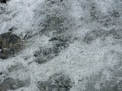 Ice clings to the rock, crystalline frost meets the stone, winter's cold embrace