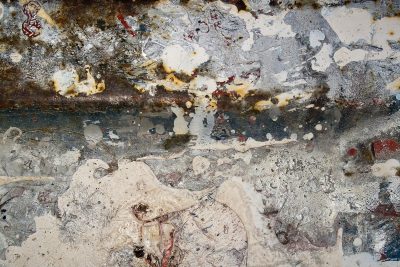 White paint splashes out, silver metal shows beneath, rust blooms in the dark