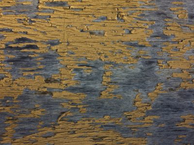 Yellow paint flakes, dark grain waits beneath the skin, wood holds the old years