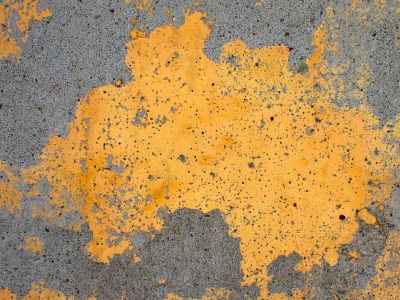 Yellow skin flakes away, jagged grey shows beneath, grit marks the finish