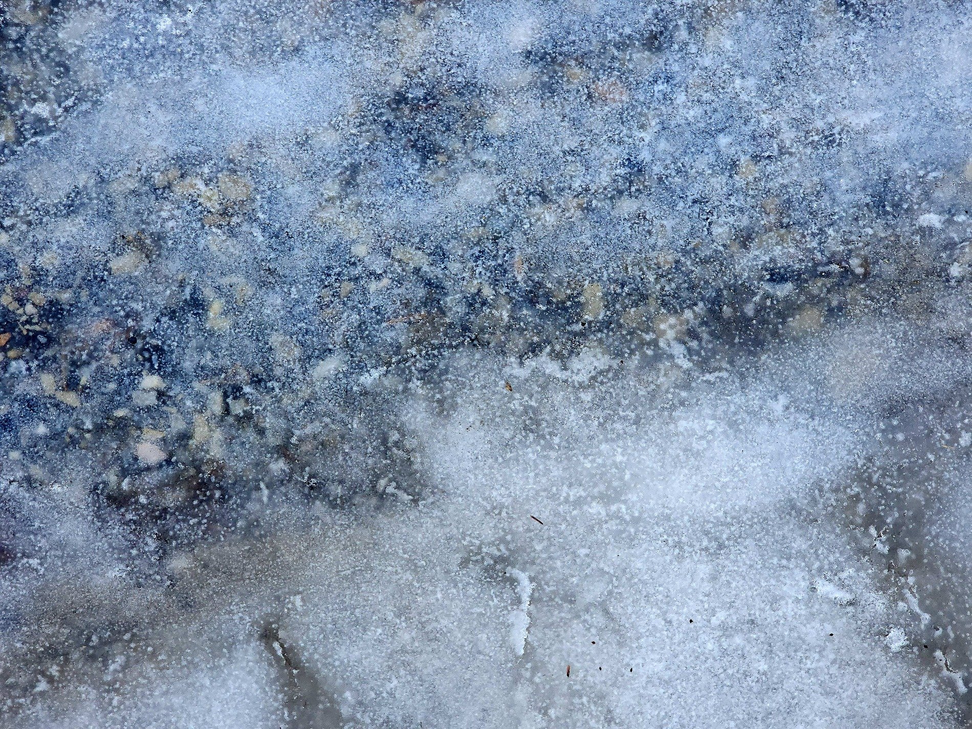White frost meets the blue, cold ice coats the heavy grit, winter takes the ground
