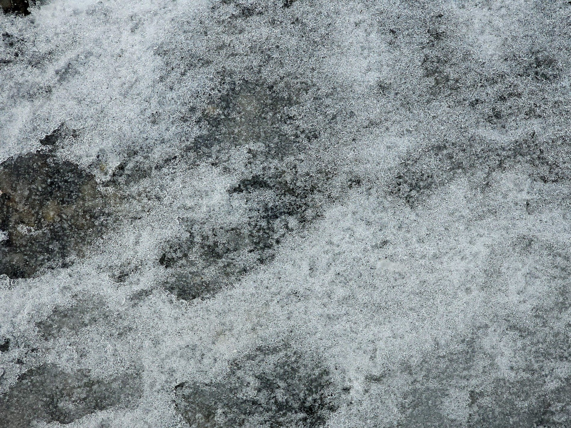 Ice clings to the rock, crystalline frost meets the stone, winter's cold embrace