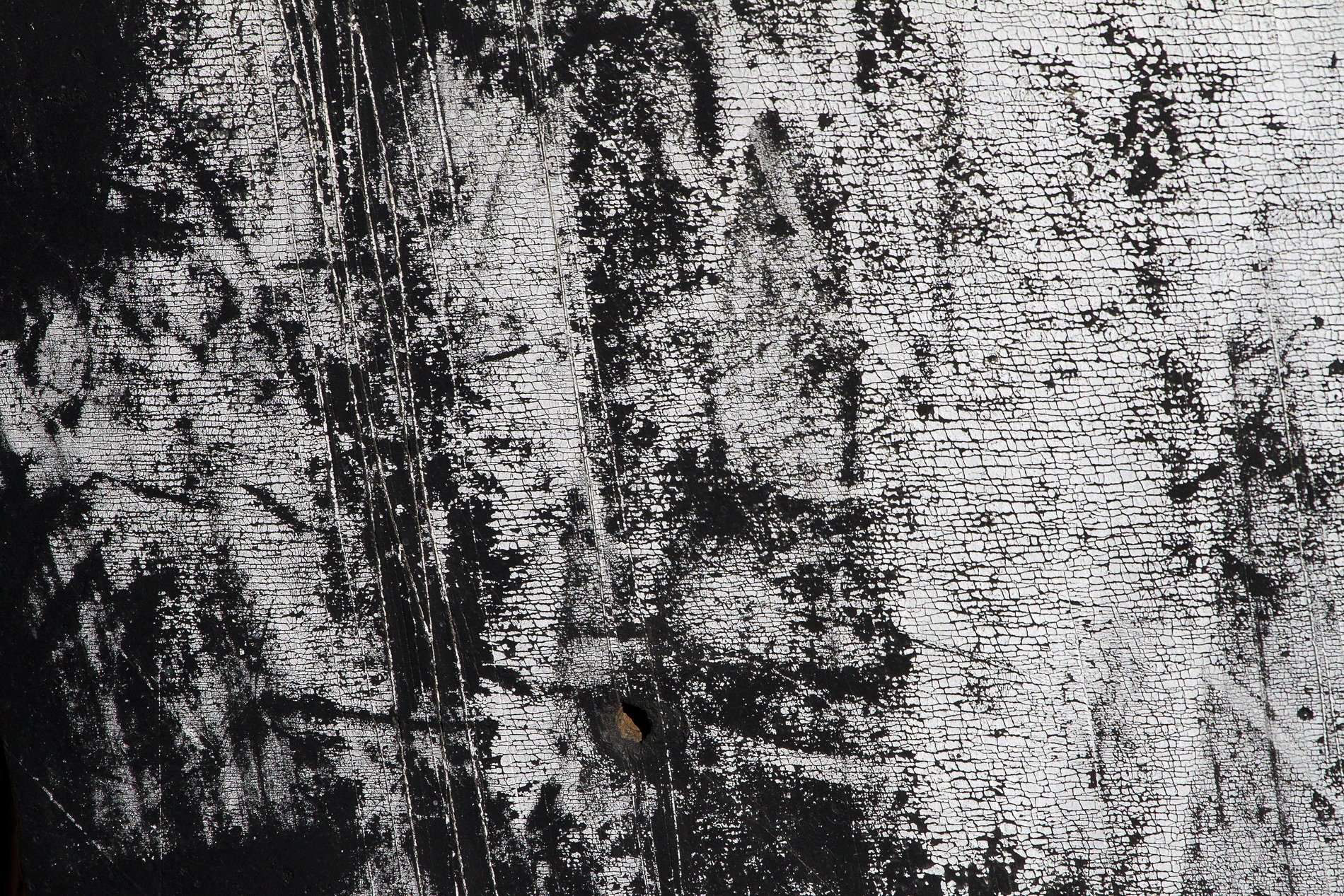 White paint flakes away, black skin waits beneath the cold, grit holds the pattern