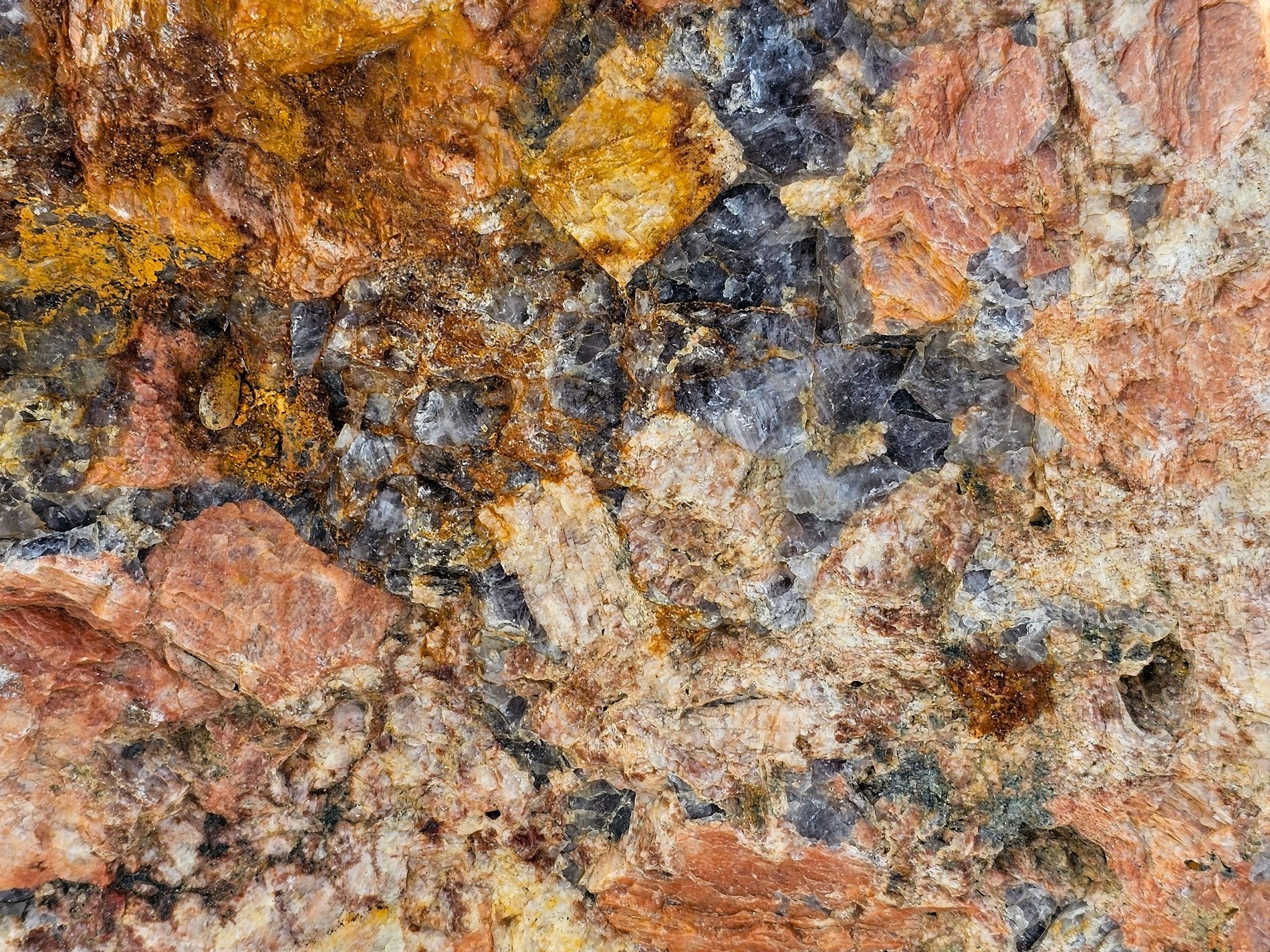 Crystals catch the light, orange veins split ancient rock, earth's textured story