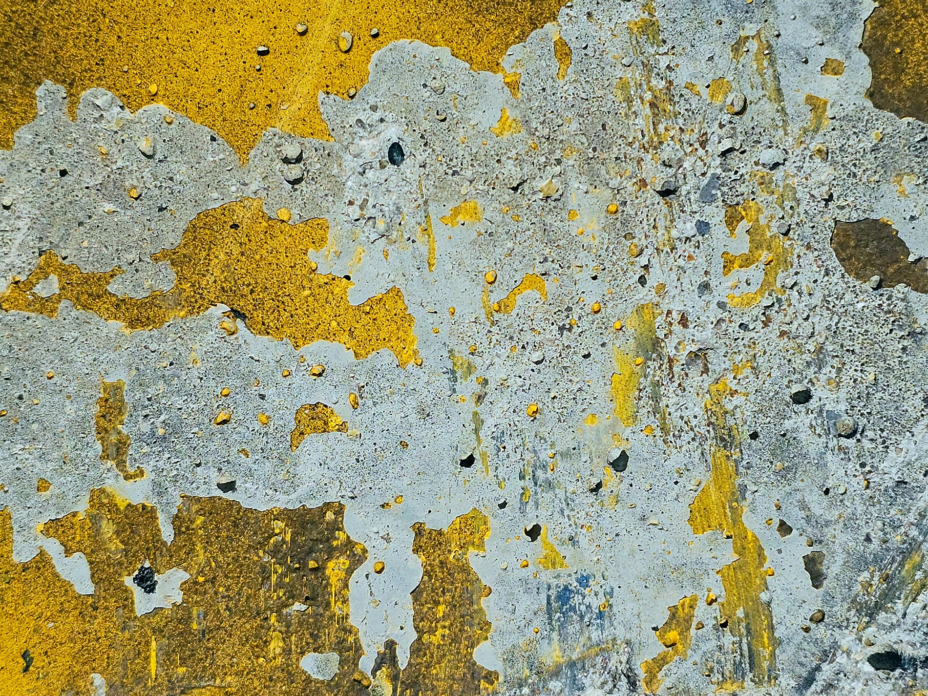 Yellow paint peels back, grey concrete holds the surface, time wears down the line.