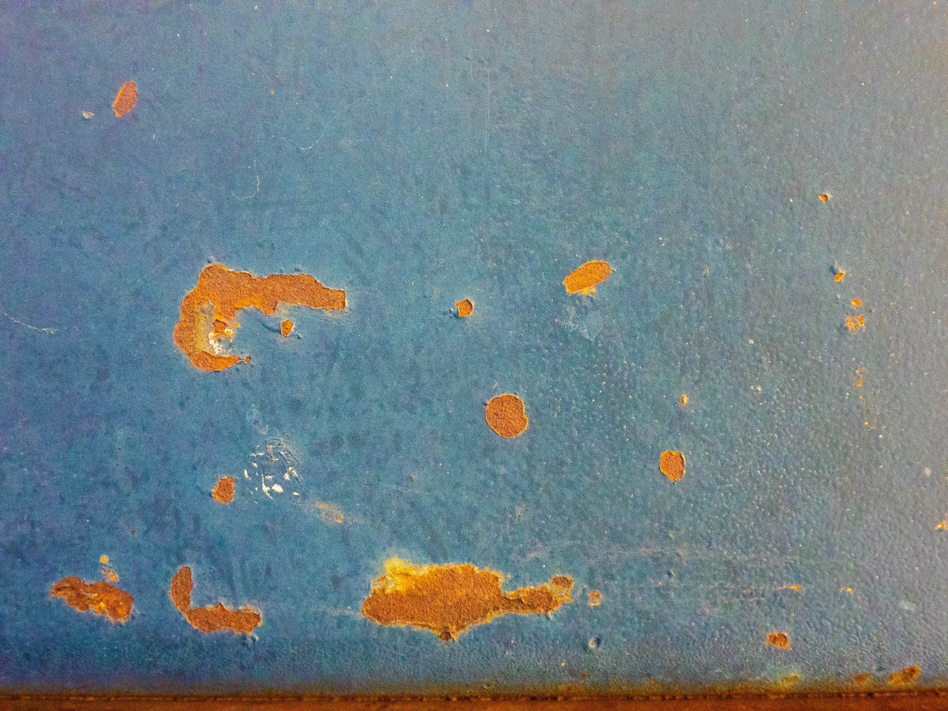 Blue mist holds the field, orange spots claim the metal, grit marks the finish