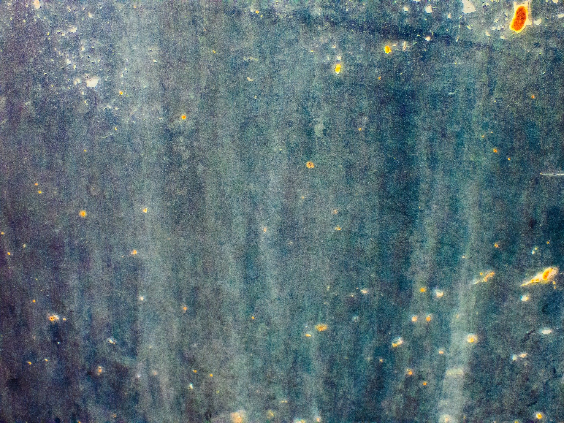 Faded teal on steel, amber rust dots start to bloom, weathered metal stays