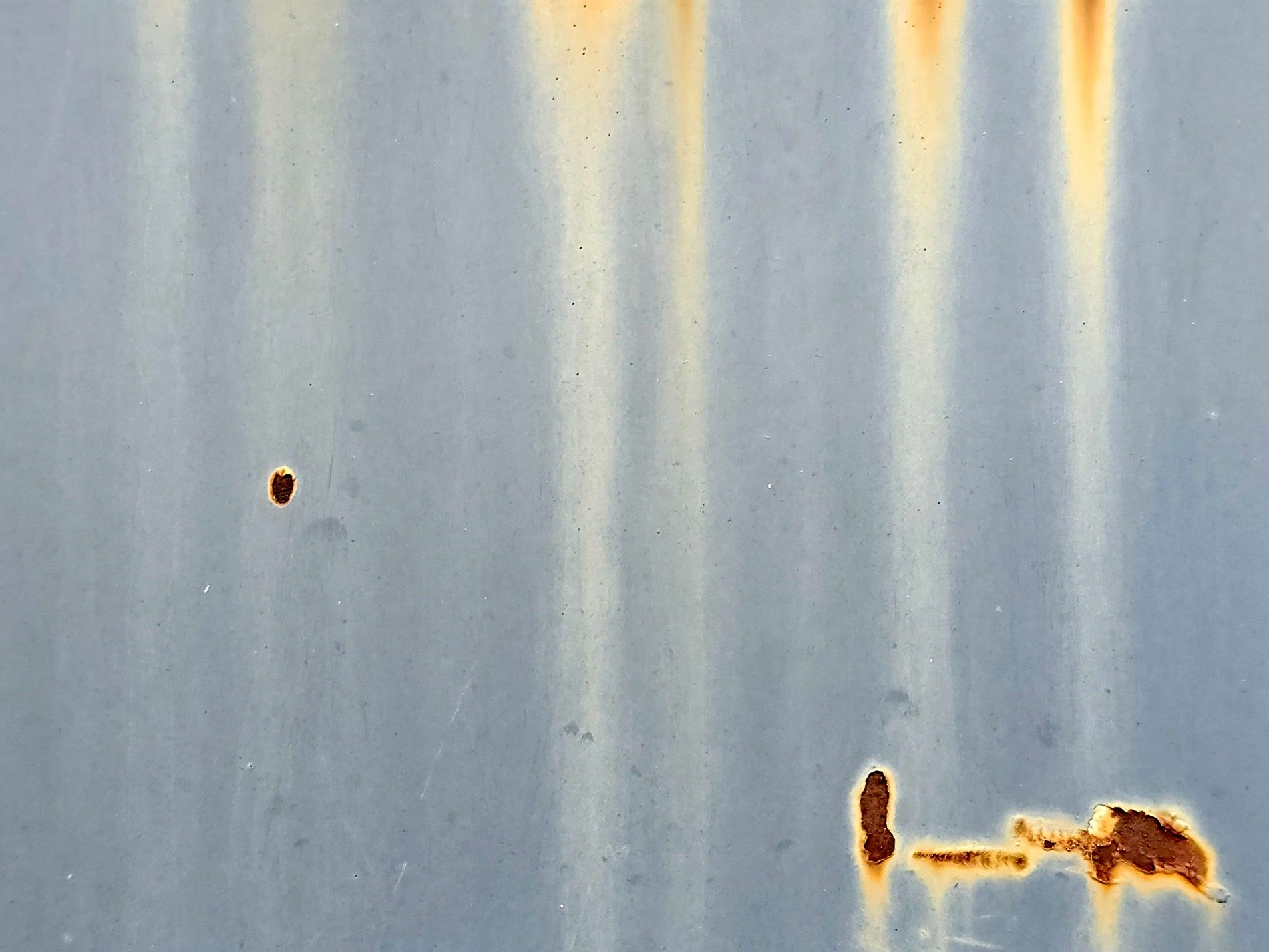 Blue paint fades away, orange rust bleeds through the steel, marks of time remain