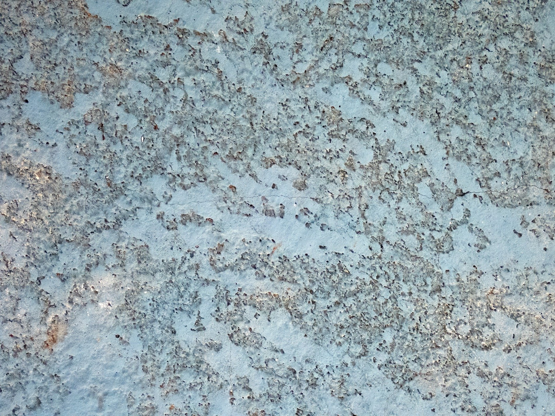 Blue paint fades away, rough grey concrete pits the wall, marks of age remain