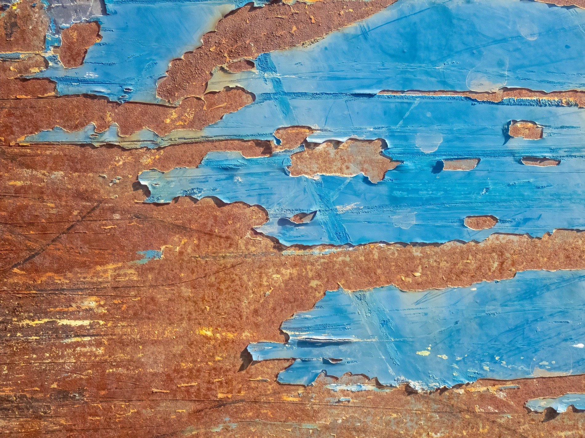 Blue paint flakes away, rusted iron bares its soul, time peels back the layers