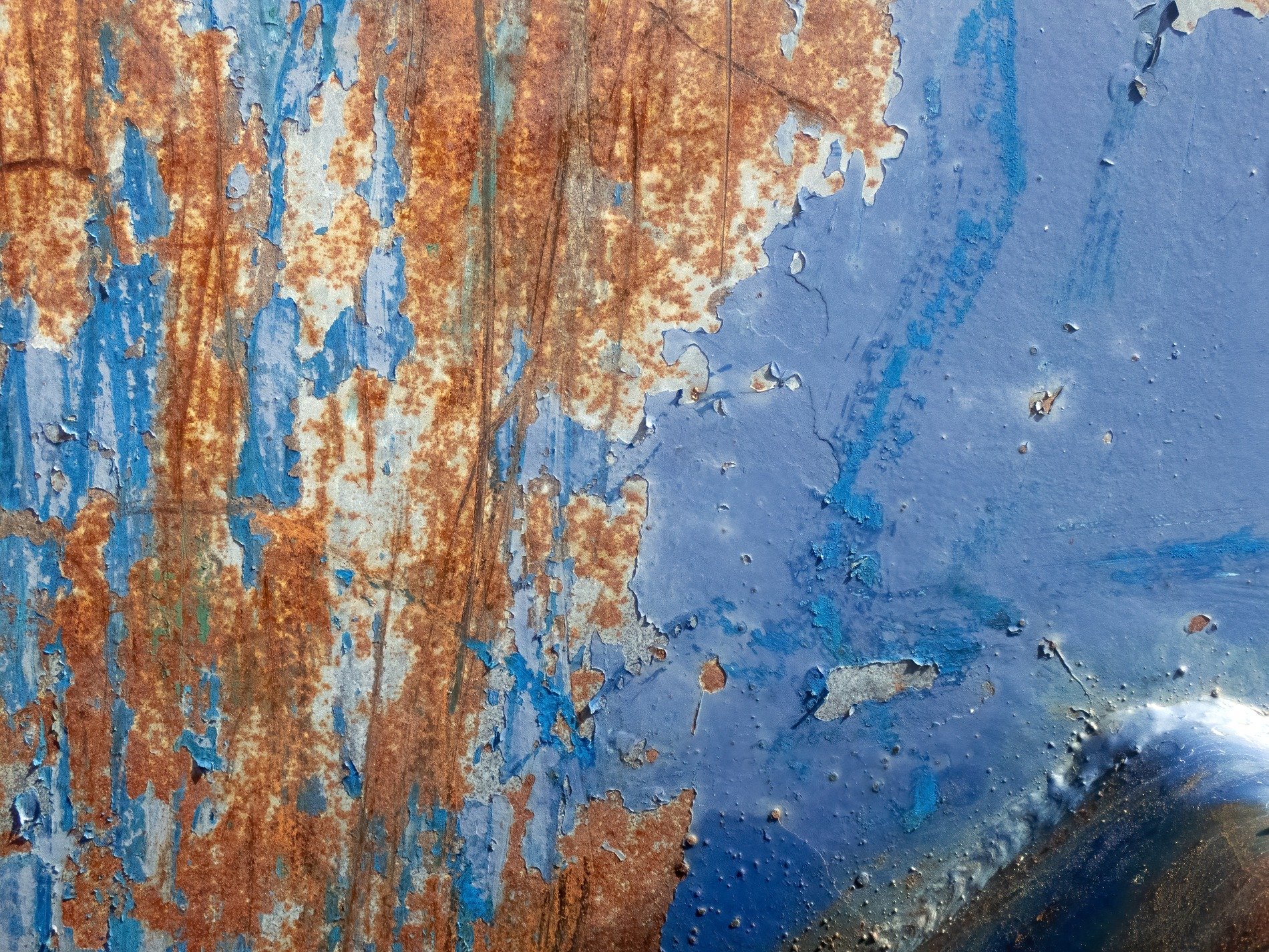 Blue paint peels away, rust creeps through the heavy steel, texture of decay