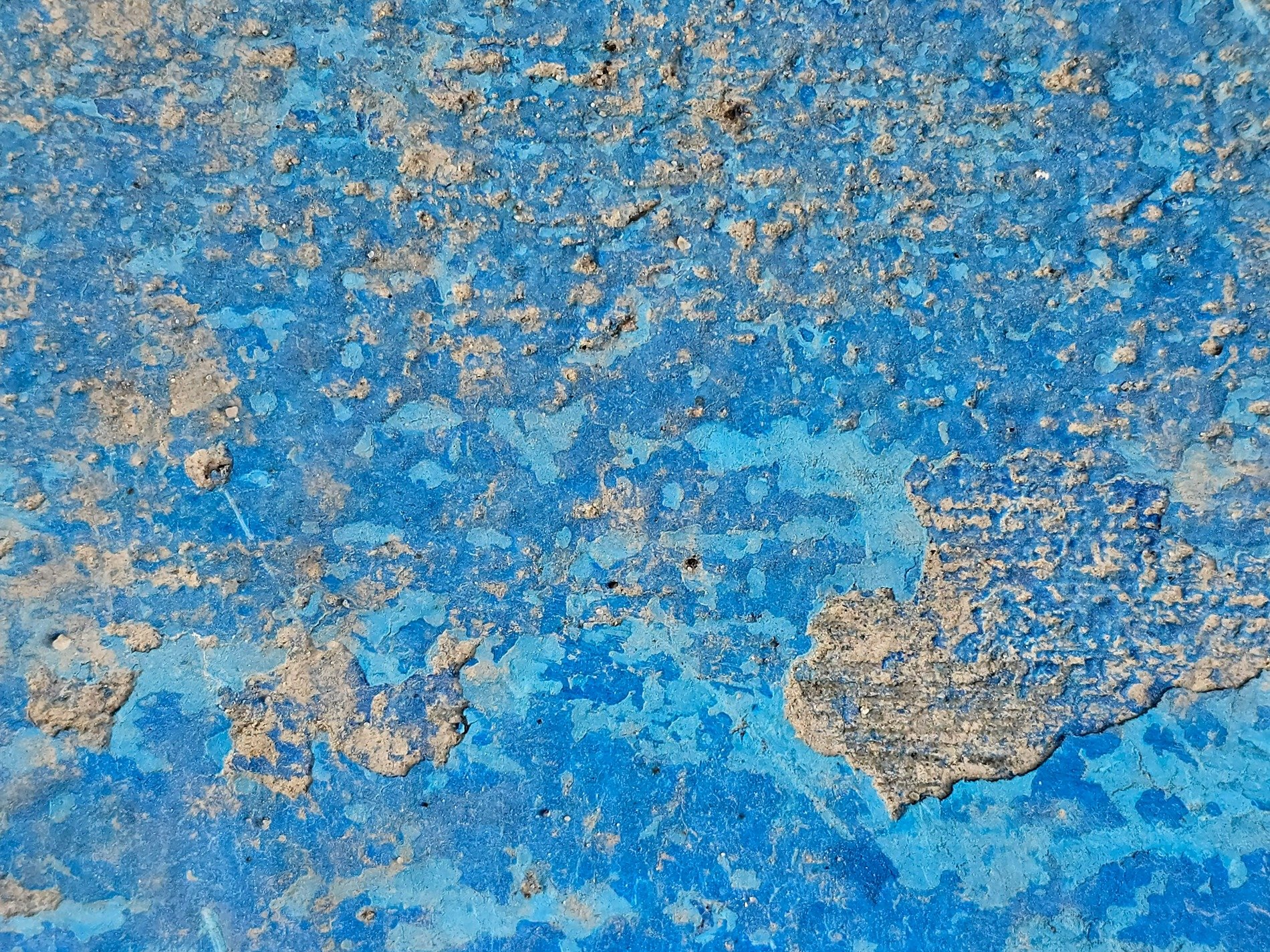Blue paint wears away, rough stone surface shows through, weathered by the years