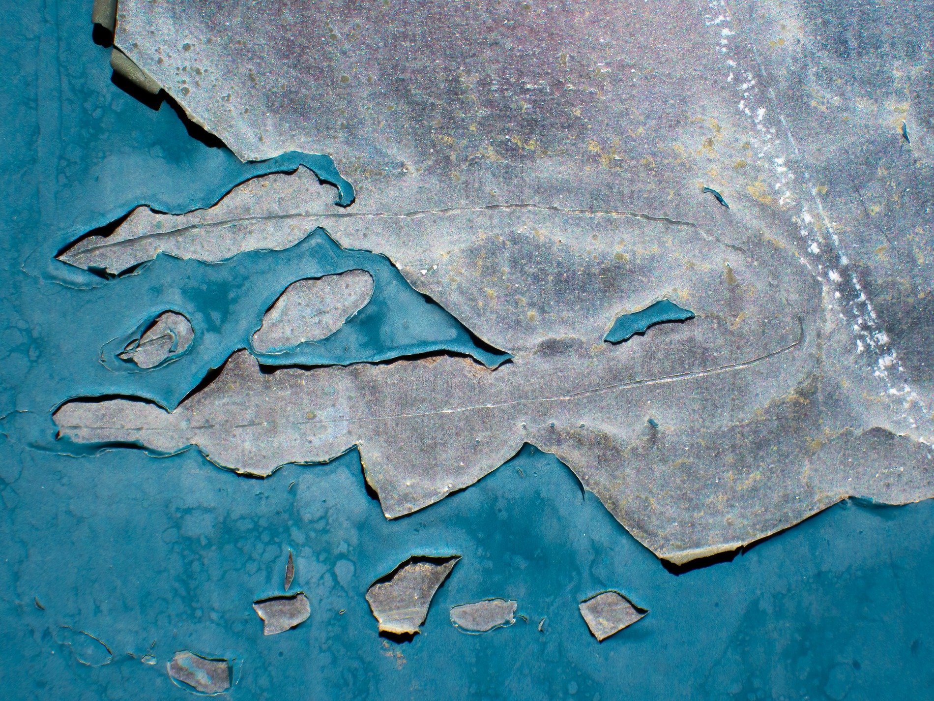 Blue skin flakes away, jagged edges meet the light, grit marks the finish