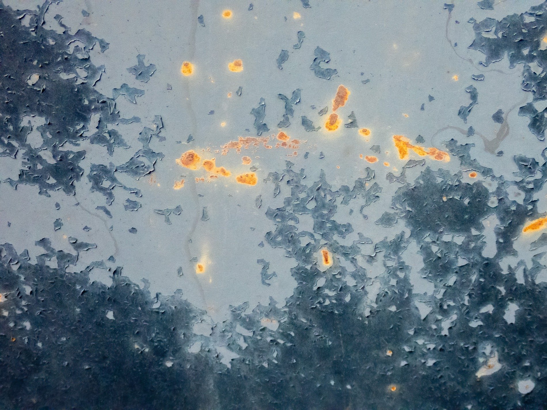 Blue skin flakes away, orange spots claim the metal, grit marks the finish