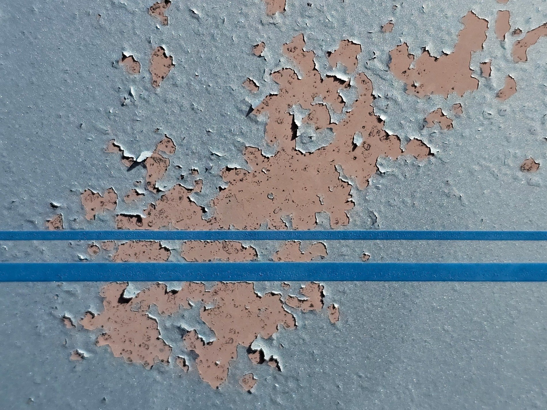 Blue skin flakes away, tan layers show the surface, twin lines cross the frame