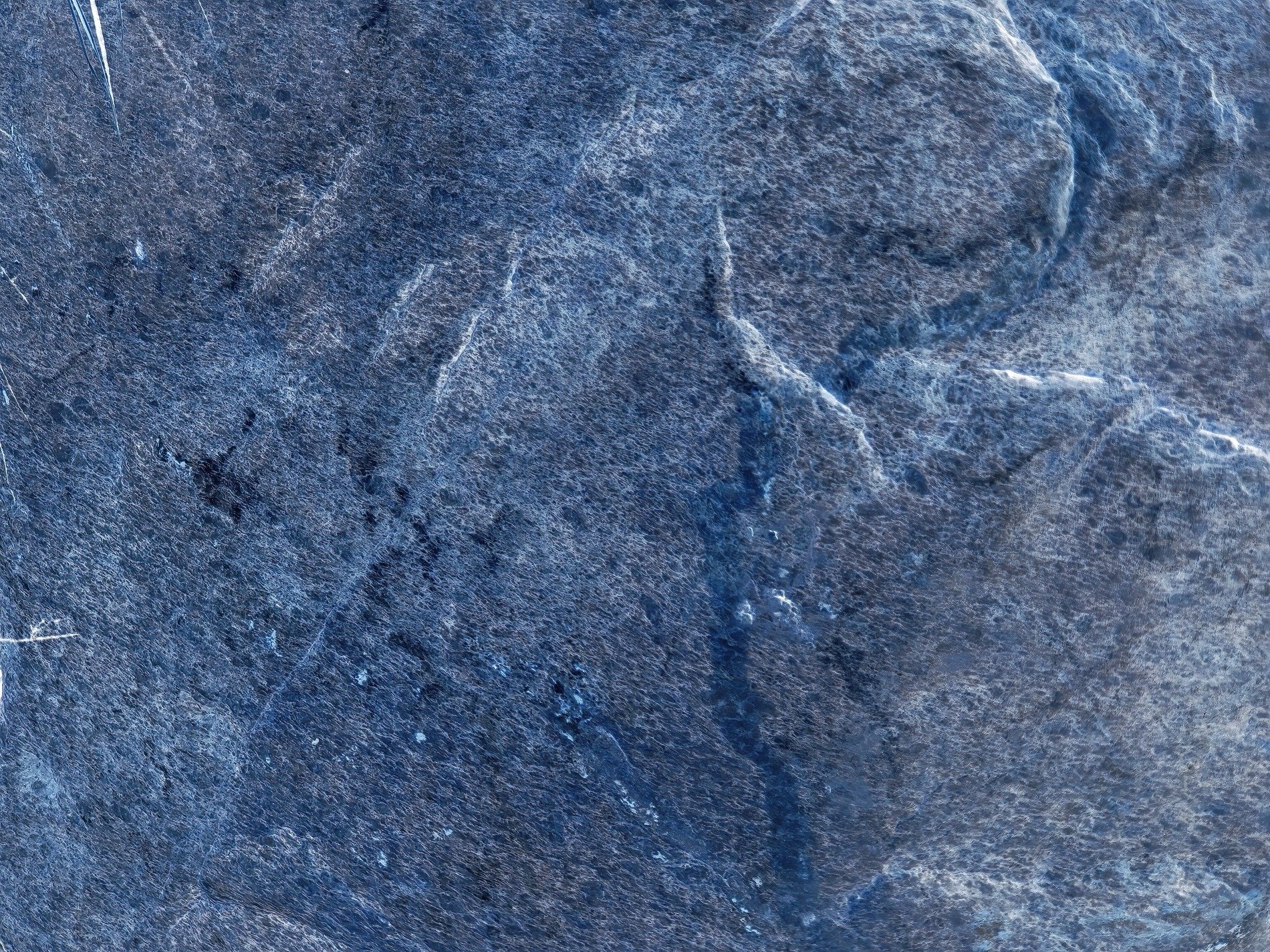 Blue stone wears its age, ridges catch the fading light, rough paths cross the face