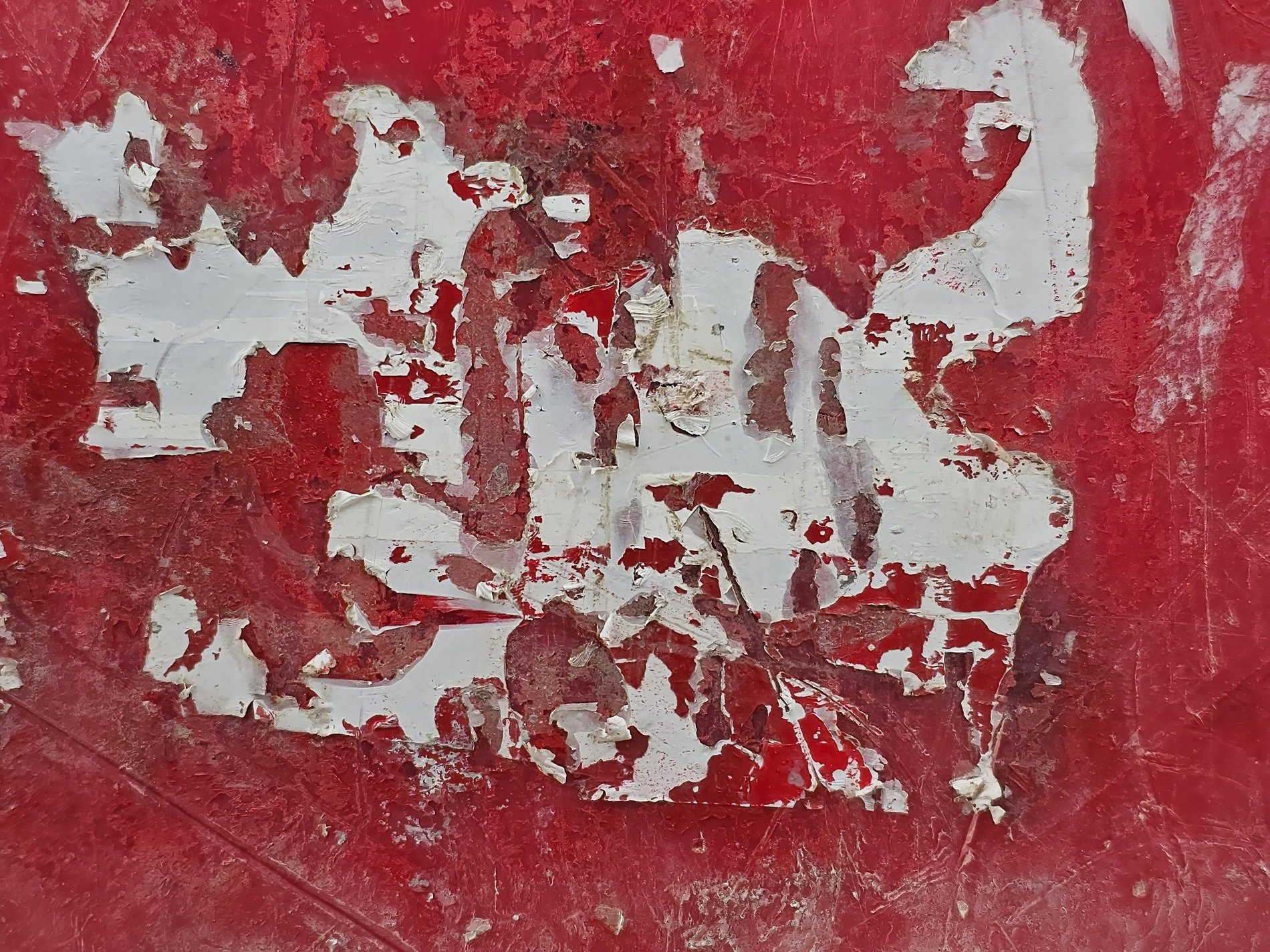 Crimson surface wears, white fragments cling to the red, paper torn by time