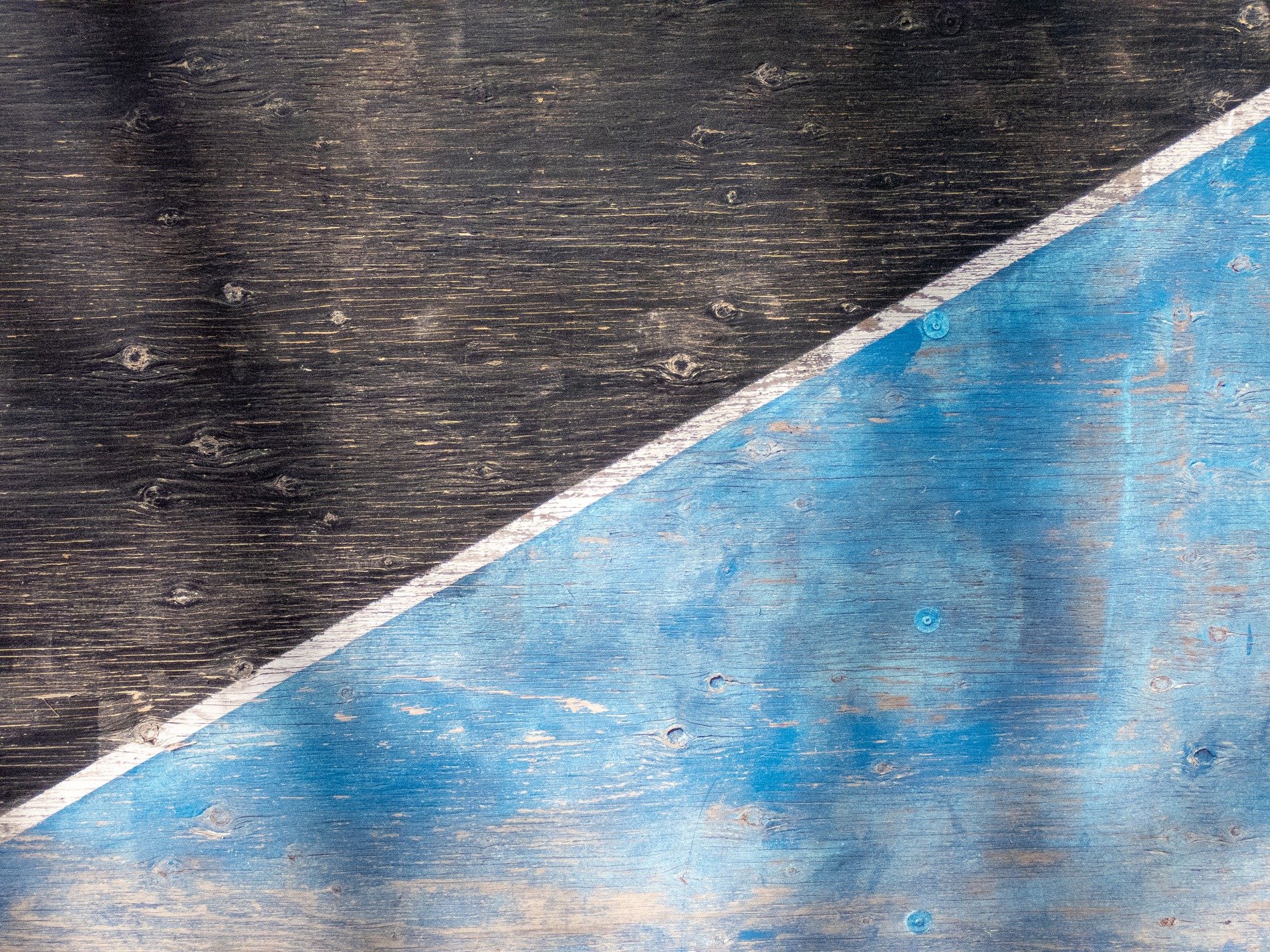 Dark fields meet the blue, diagonal lines divide, light marks the surface