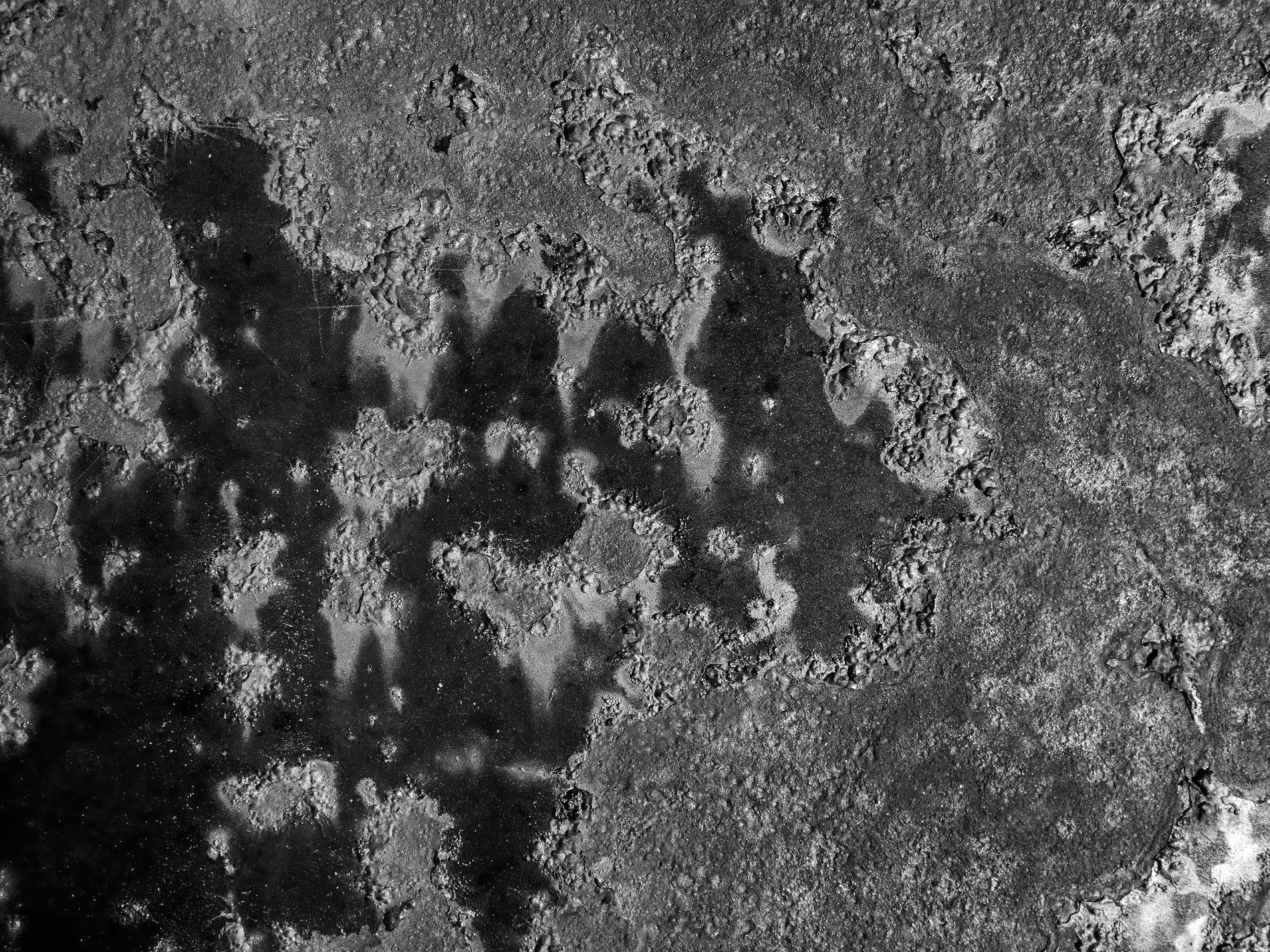 Dark pits mark the light, jagged grit claims the heavy field, paths trace the metal