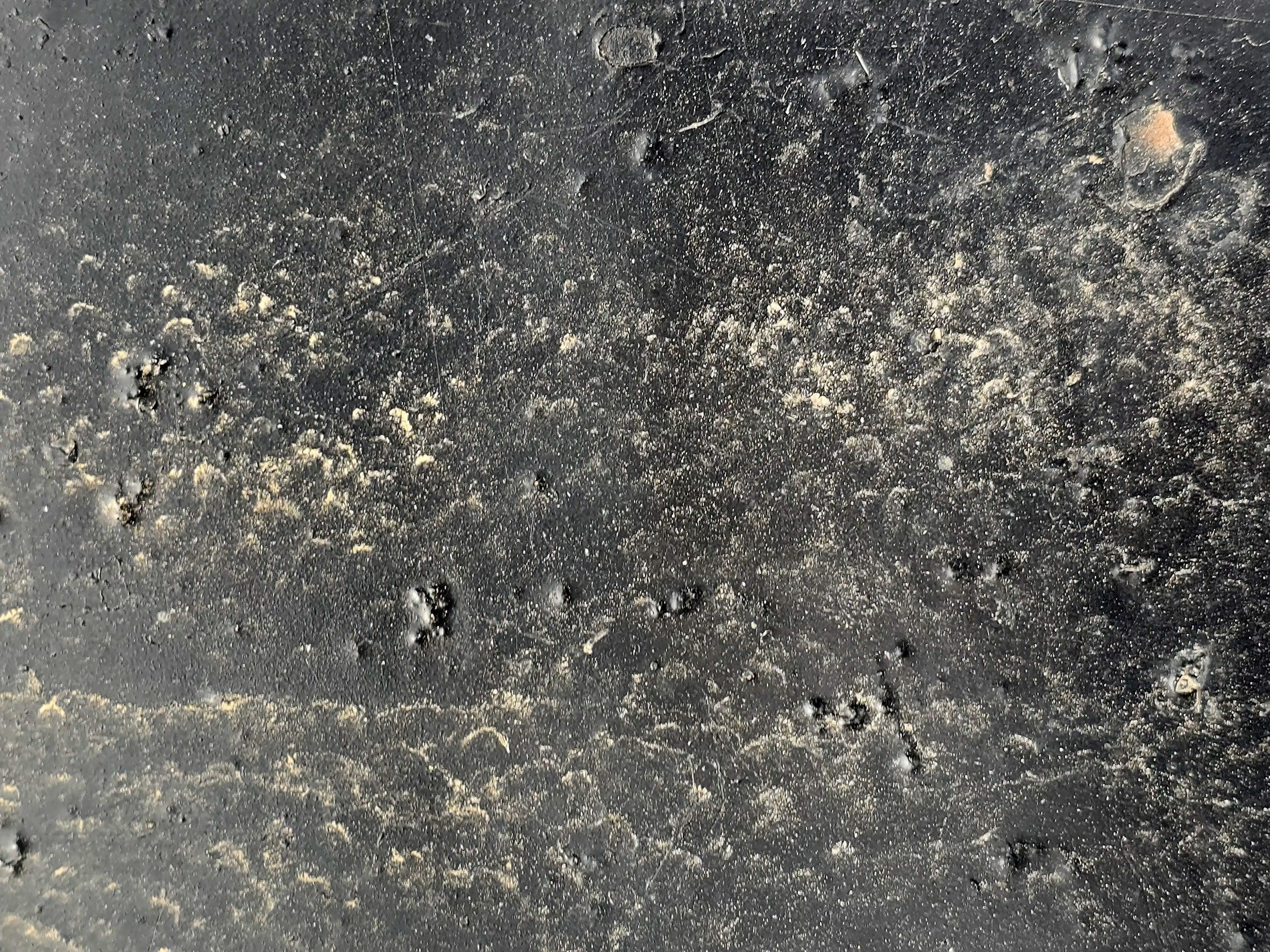 Dark surface is scarred, gritty dust clings to the paint, shadows fill the pits