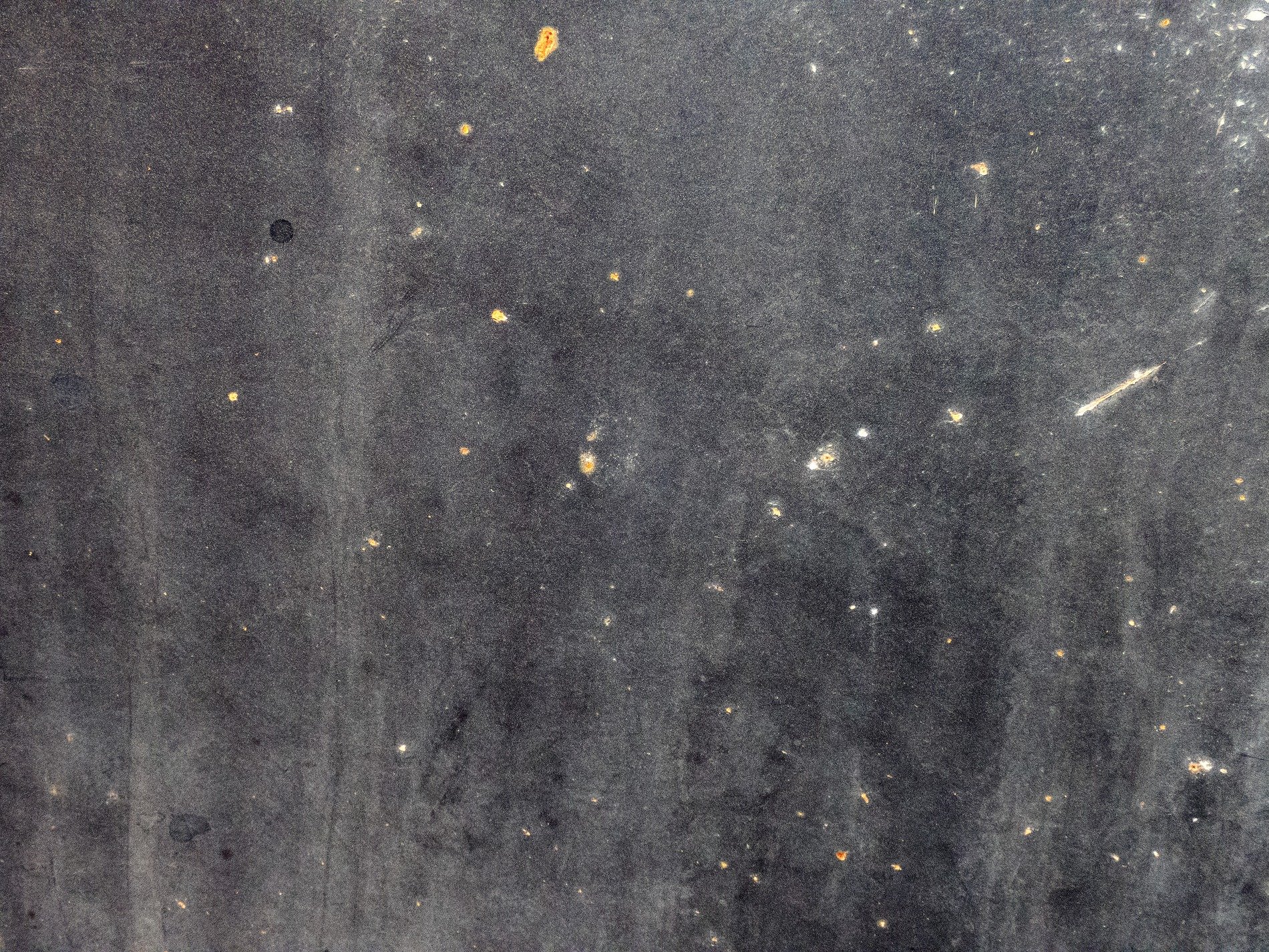 Dark void wears its scars, orange sparks in endless gray, dust clouds hold the light