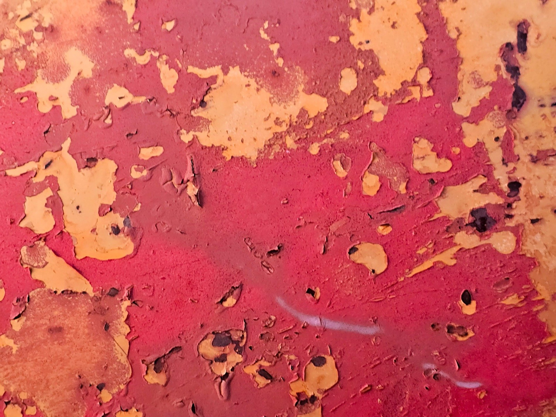 Red flakes fall away, golden patches show beneath, layers crack and peel