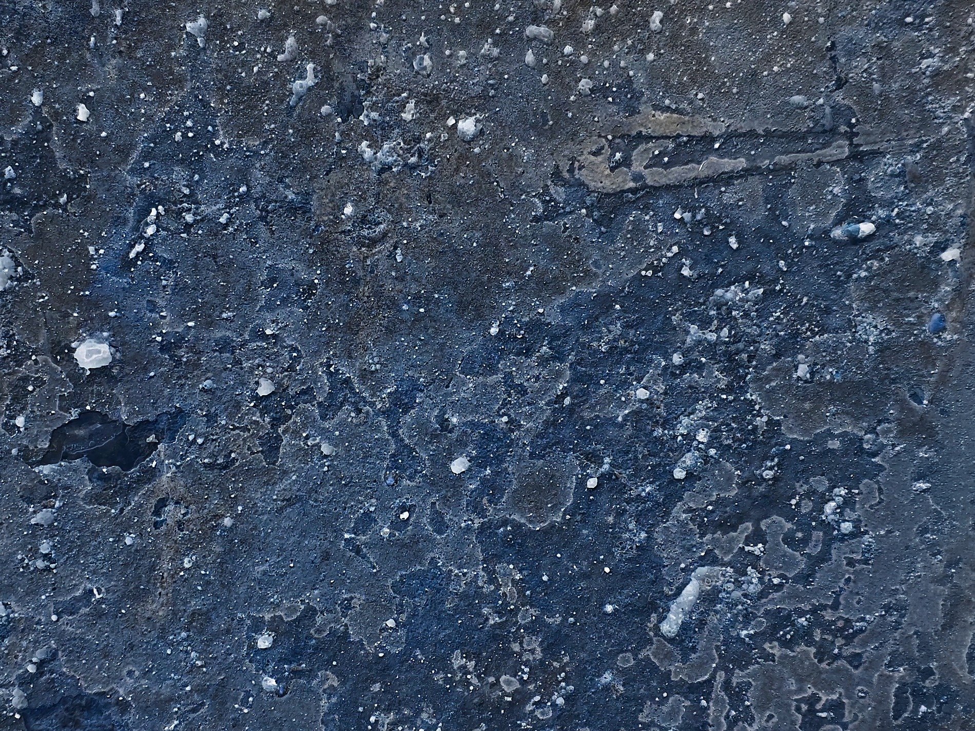 Deep blue grit and grime, white specks dot the weathered stone, cold texture endures