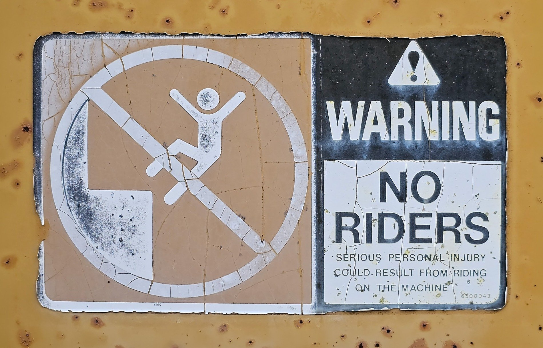 Faded warning signs, yellow metal cracks and rusts, stay off the machine