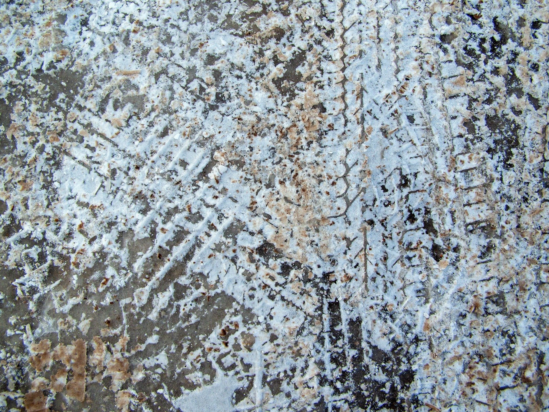Frozen white and grey, patterns etched in dirty slush, winter's heavy path