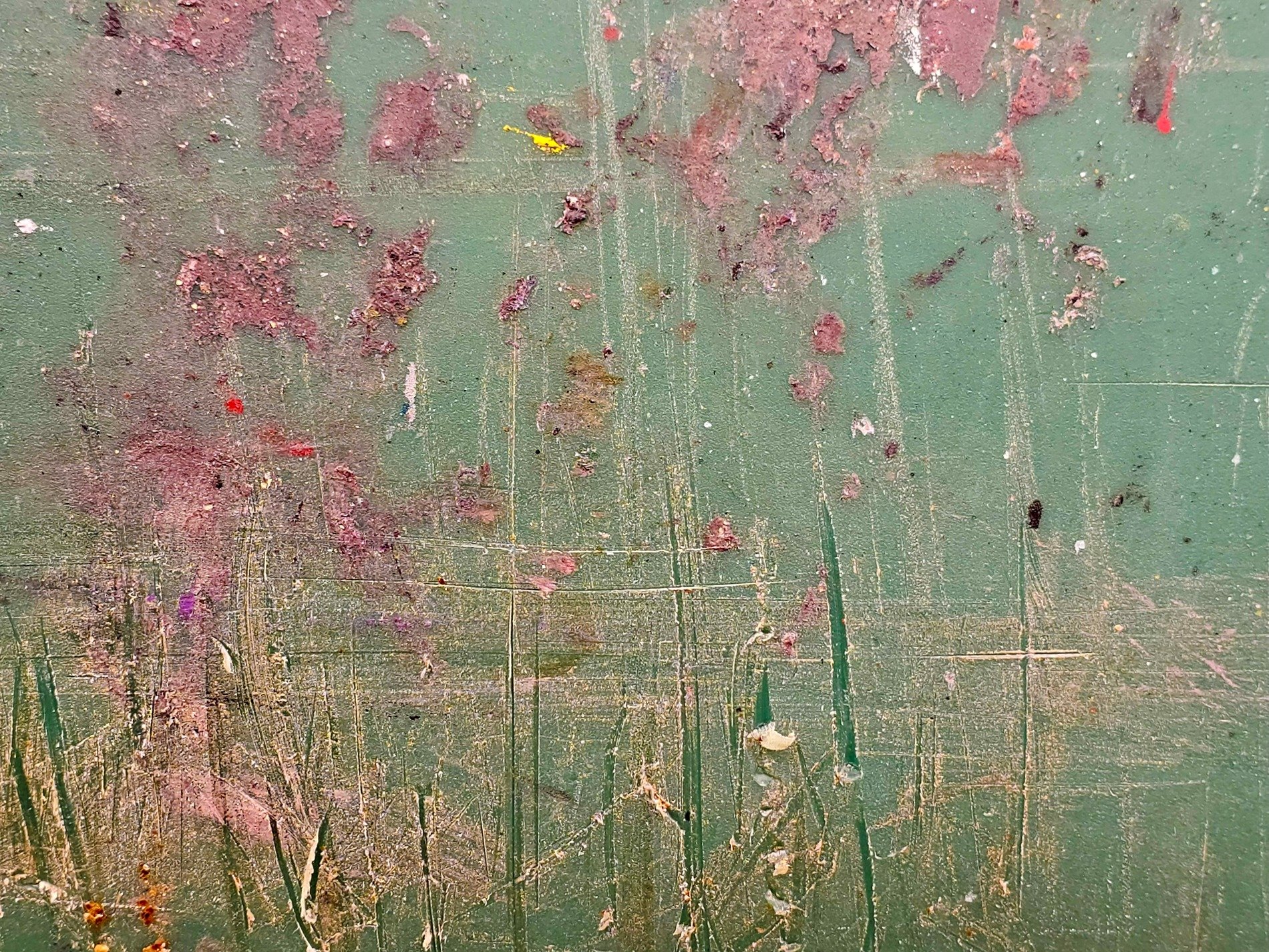 Green field worn by time, reddish scars mar the surface, deep scratches remain