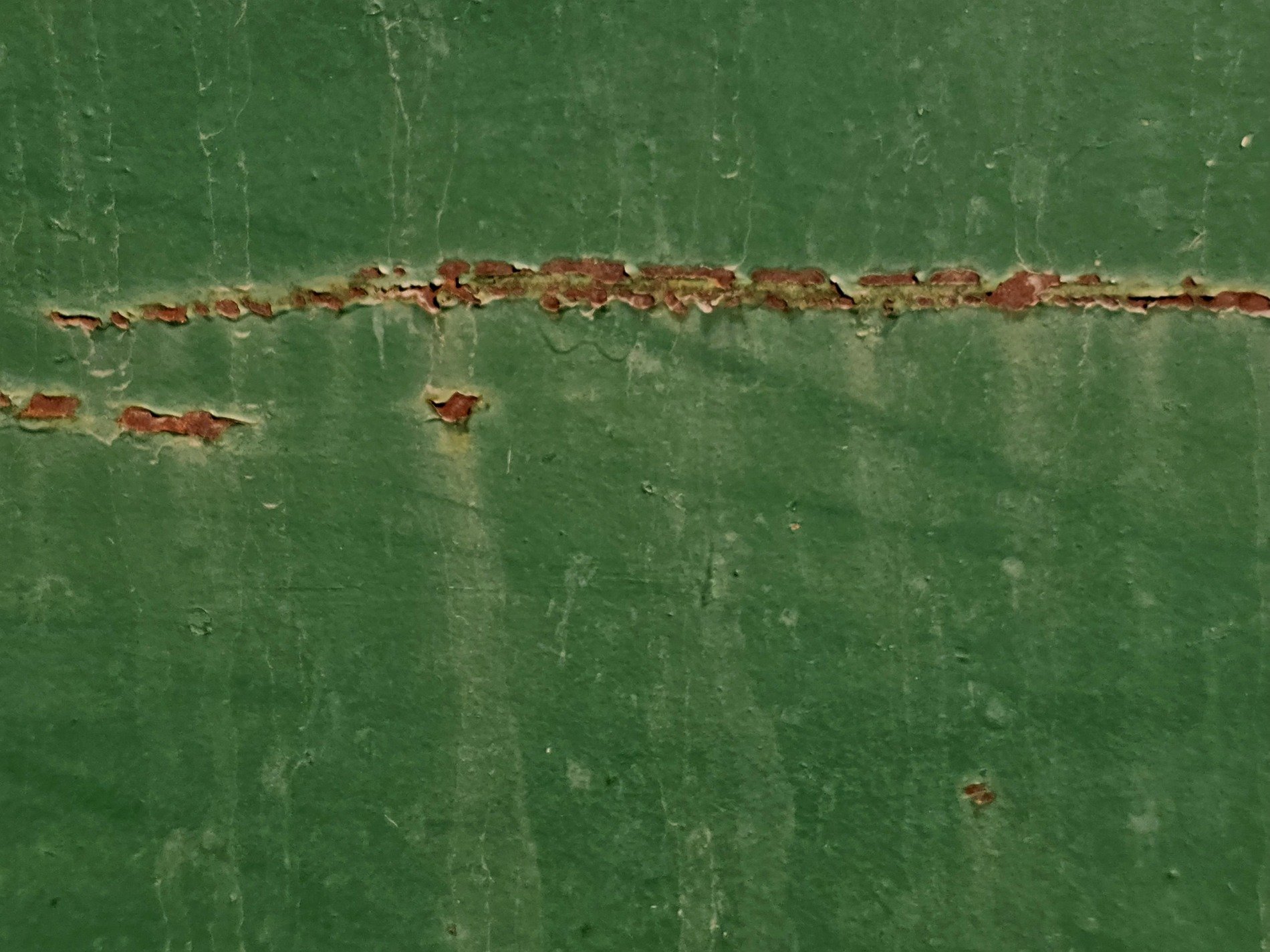 Green layers flake off, orange grit claims the surface, time leaves a thick mark