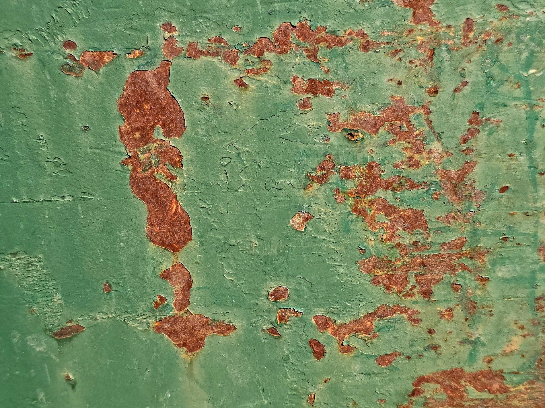 Green paint flakes away, orange grit claims the surface, time leaves a thick mark
