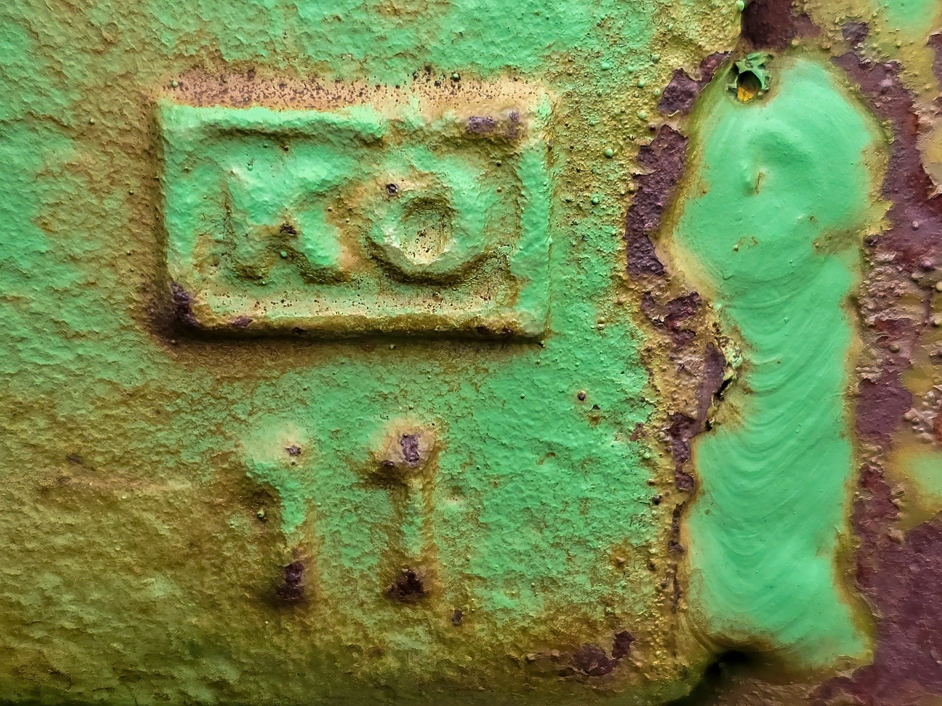 Green paint wears away, orange rust devours the iron, letters mark the past