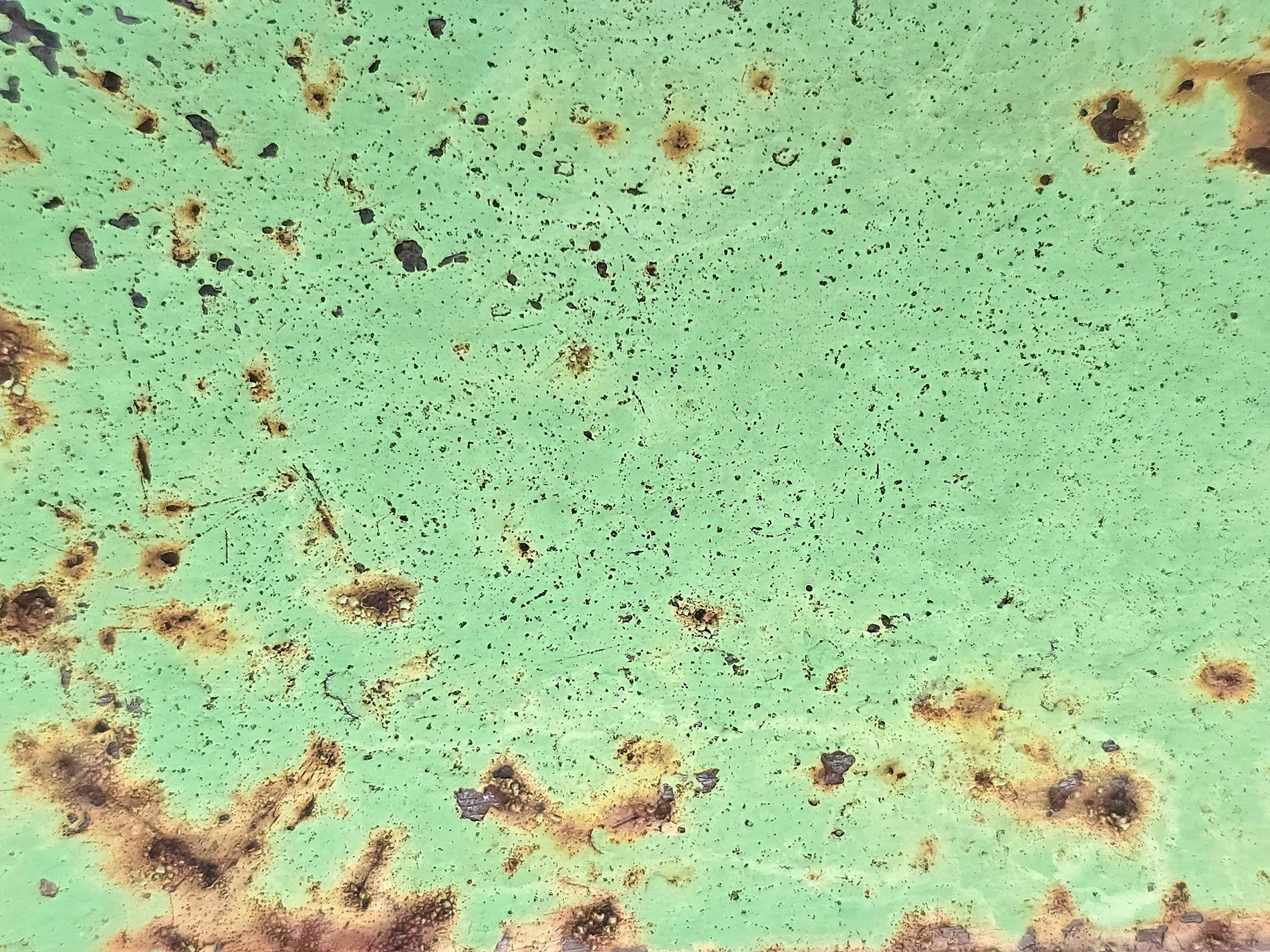 Green paint wears away, orange rust pits the surface, iron turns to dust