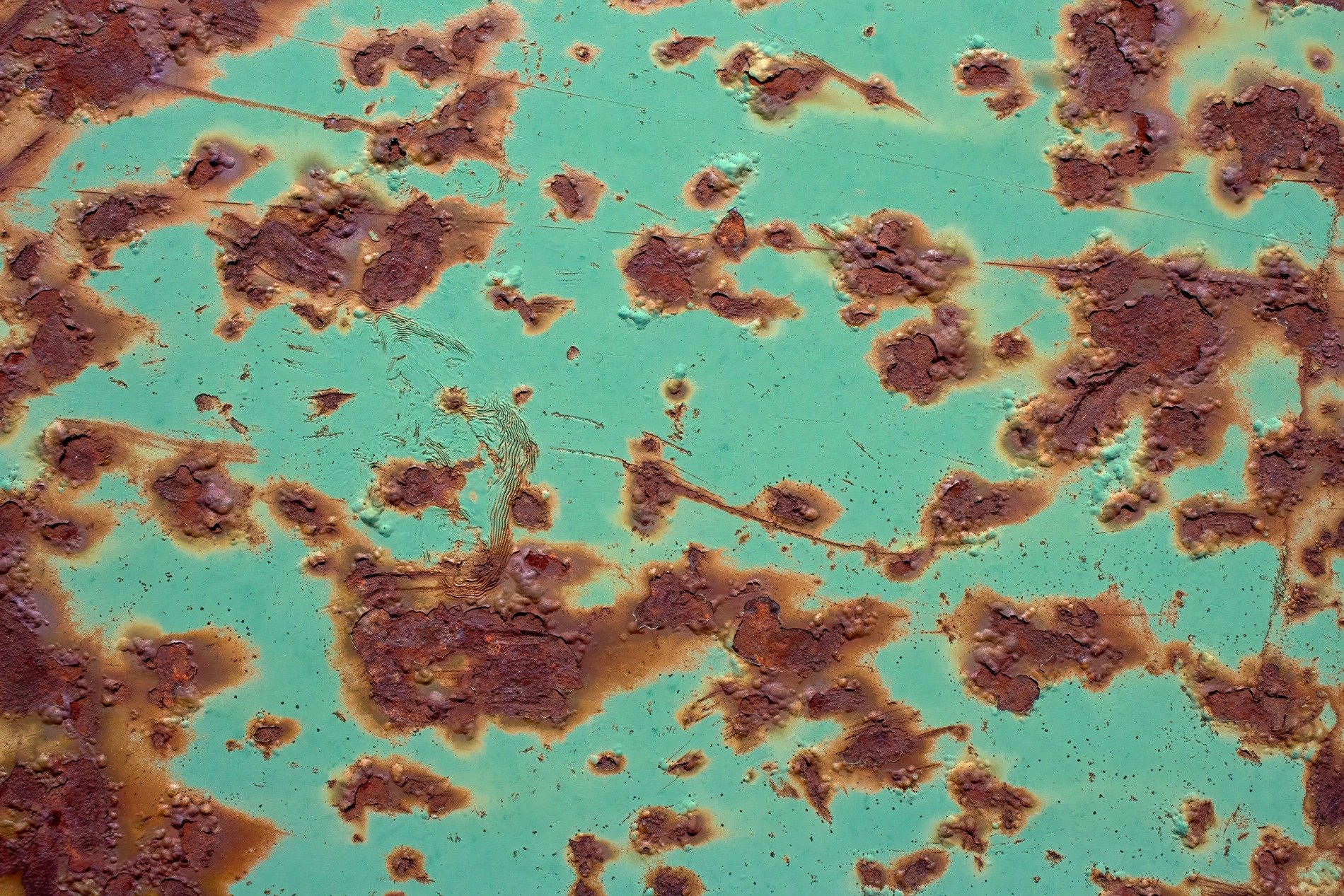 Green skin flakes away, orange pits trace the heavy metal, grit marks the finish