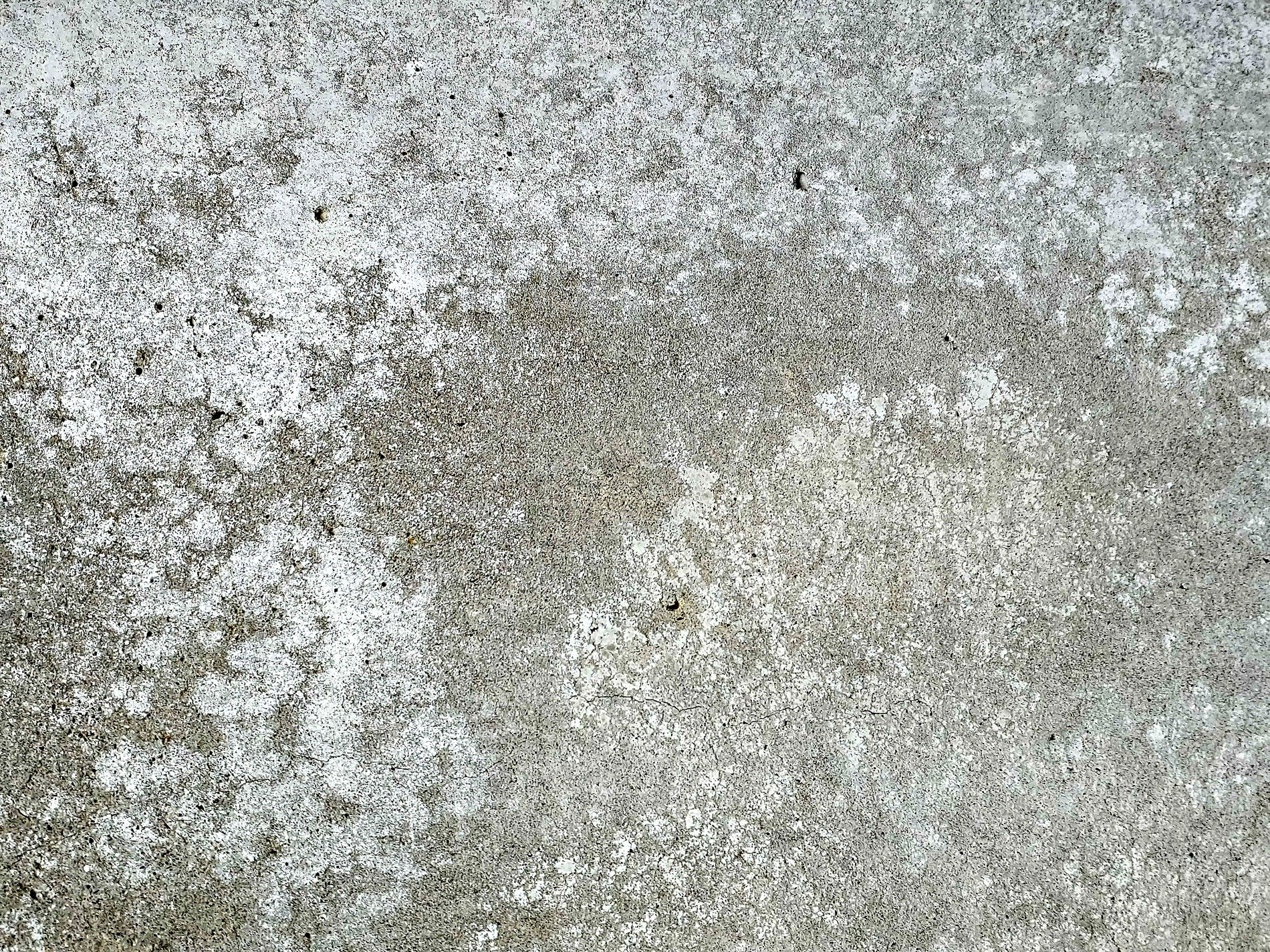 Grey dust coats the slab, thin cracks branch across the path, rough stone holds the age