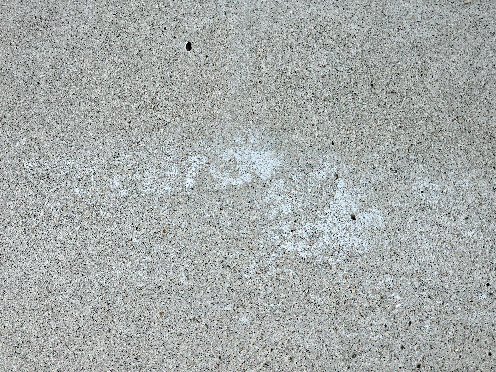 Grey grains hold the light, white ghost fades on rough concrete, silent stone endures