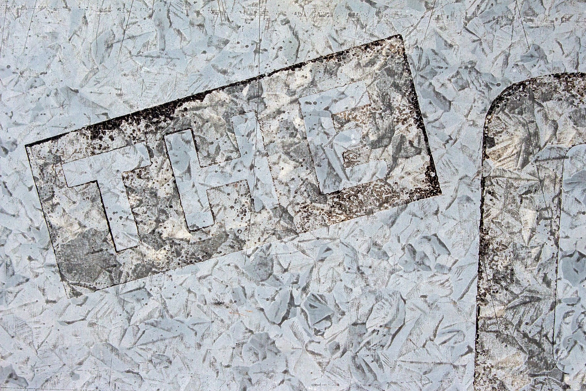 Grey patterns meet light, the script marks the metal skin, grit claims the heavy