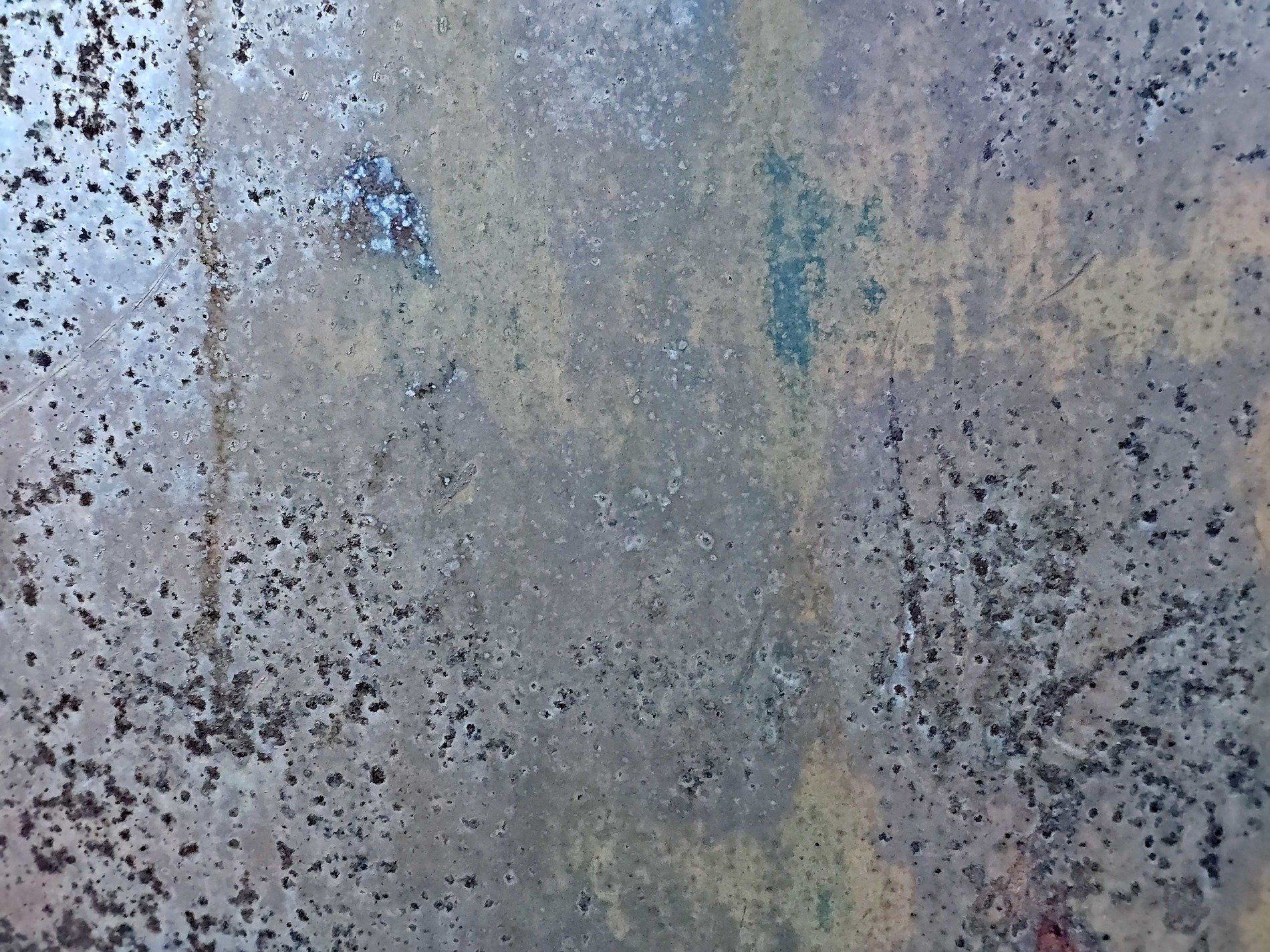 Grey pits mark the light, ancient paths trace the surface, grit claims the metal