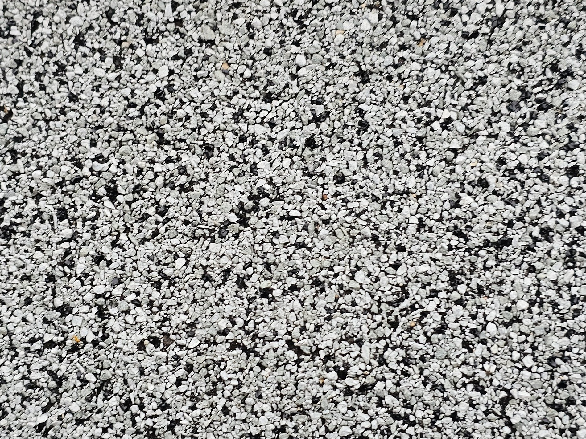 White stones on the ground, resting on a bed of black, rough and cold to touch