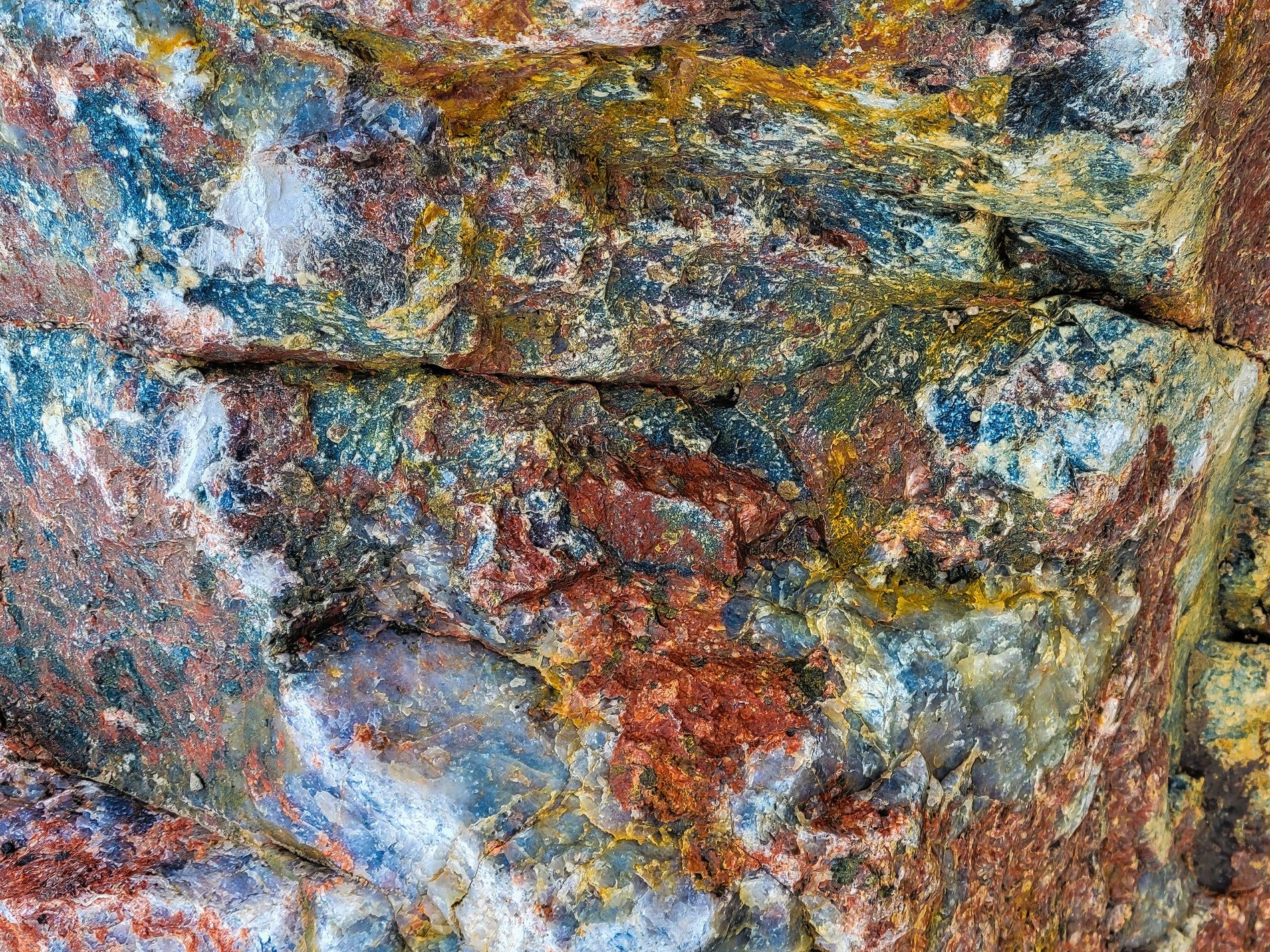 Iron stains the quartz, blue shadows hide in the cracks, earth's deep colors show