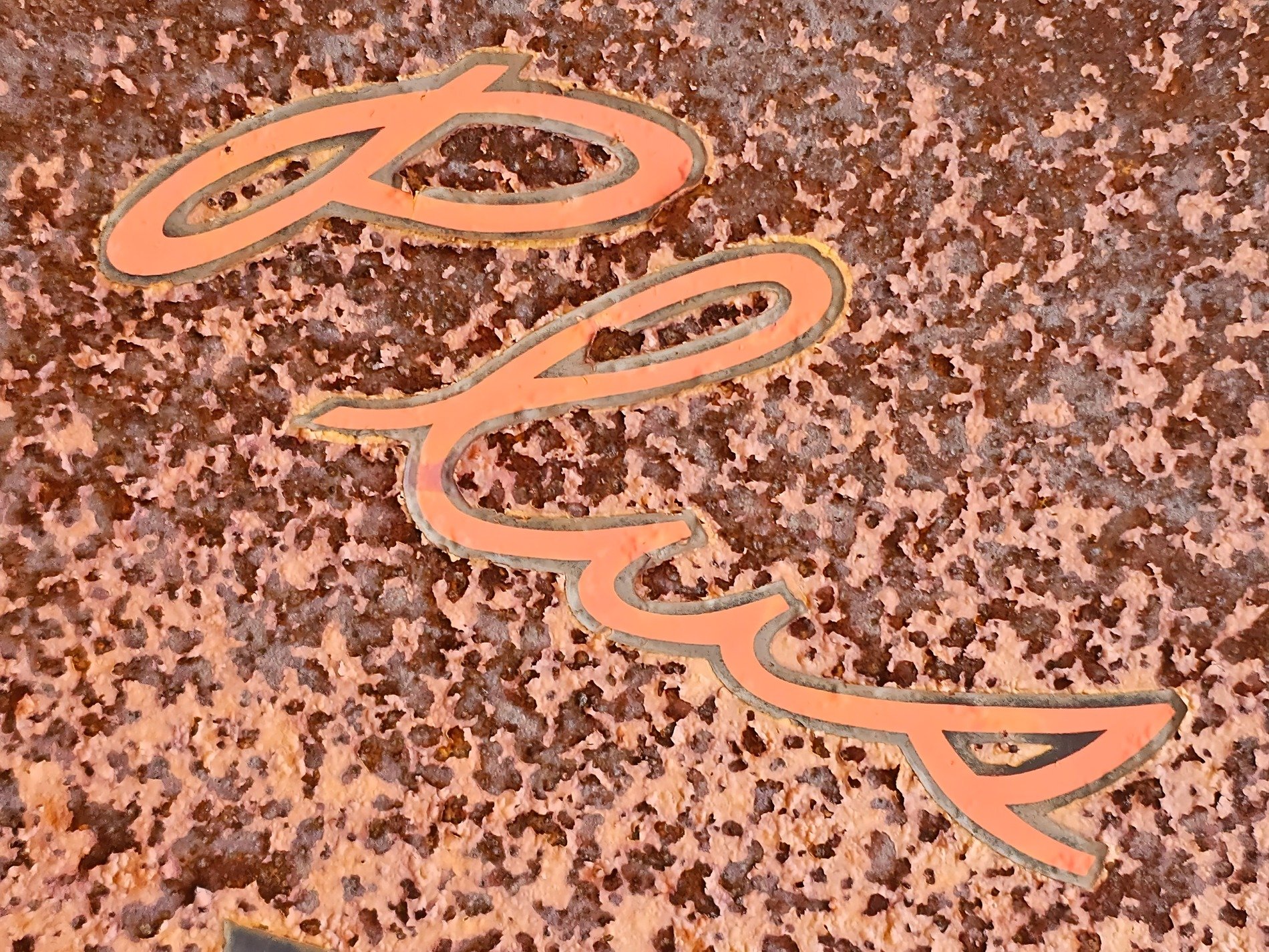 Logo paths meet the rust, heavy grit claims the surface, time marks the metal